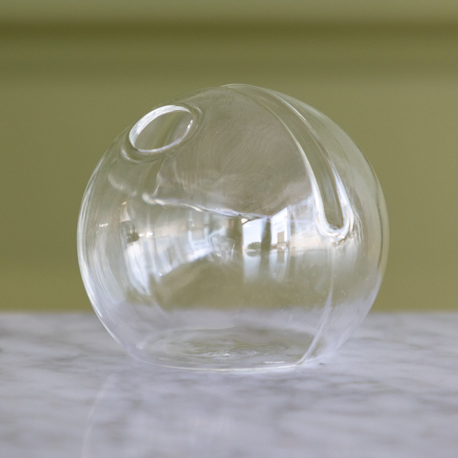 Clear glass sphere on a marble surface with a blurred background.