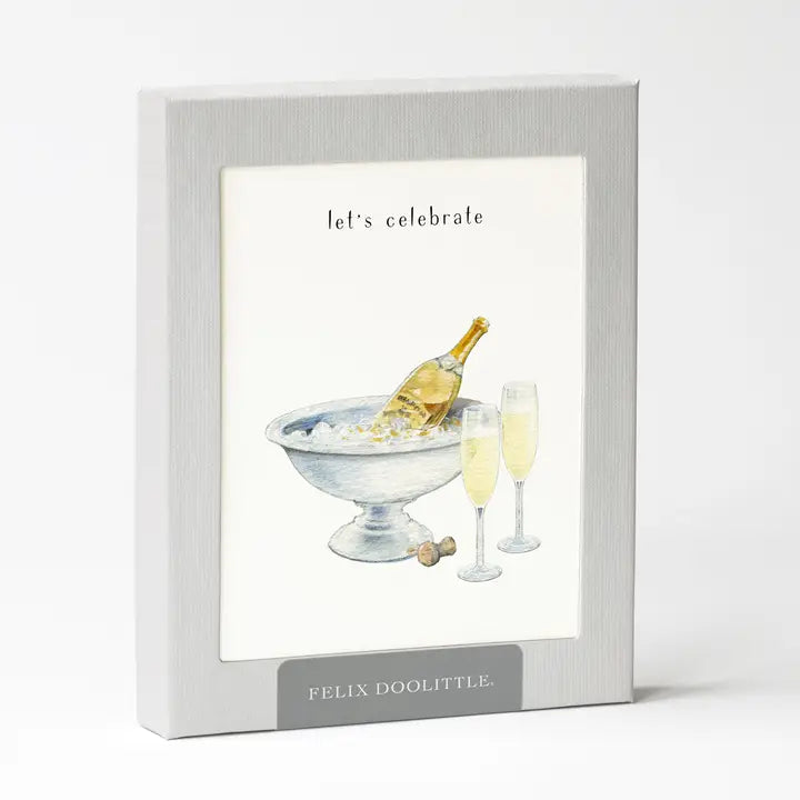 A box of cards featuring a watercolor illustration of champagne glasses and a bottle in an ice bucket, with text that says "let&