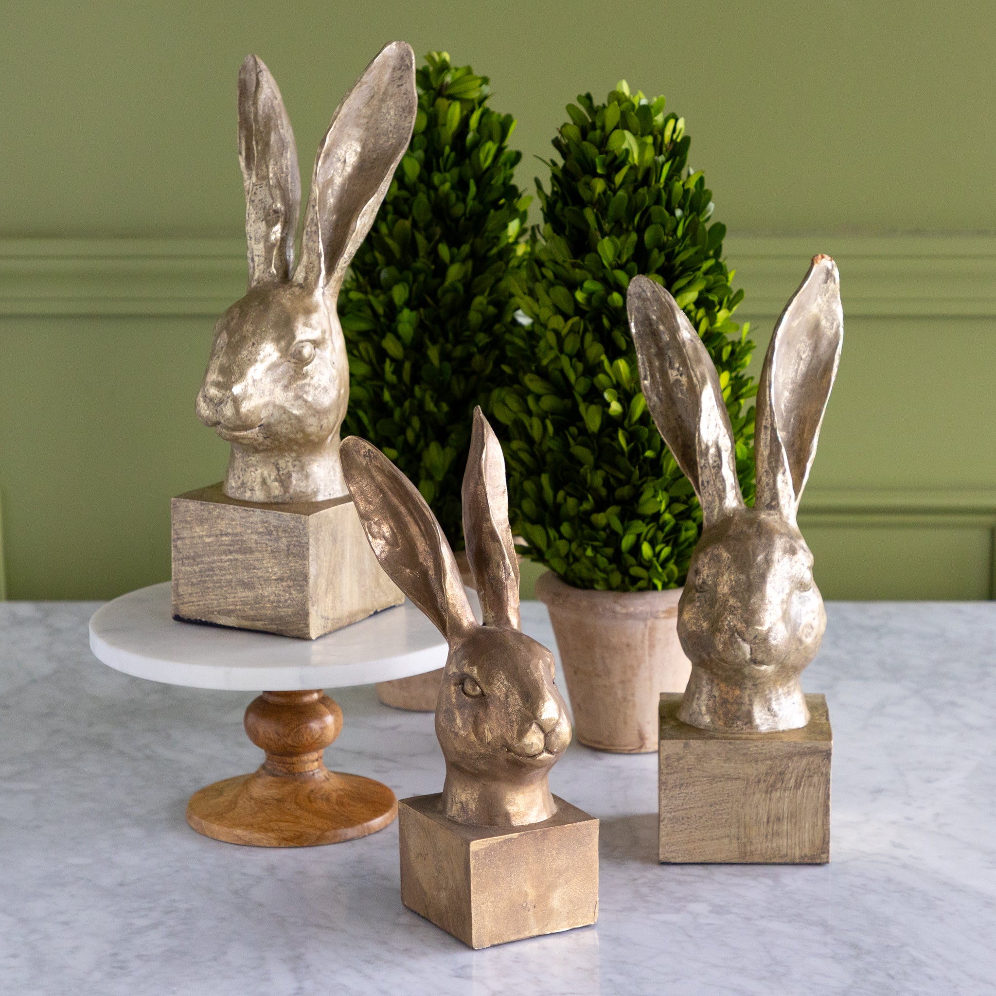 Decorative rabbit head sculptures on stands with a green wall background.