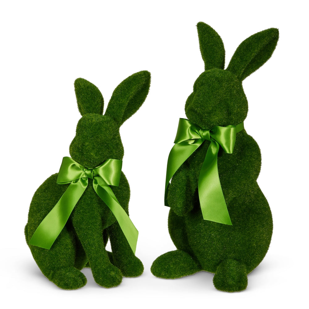 Two green decorative bunnies with green ribbons, one sitting and one on its hind legs, on a white background.