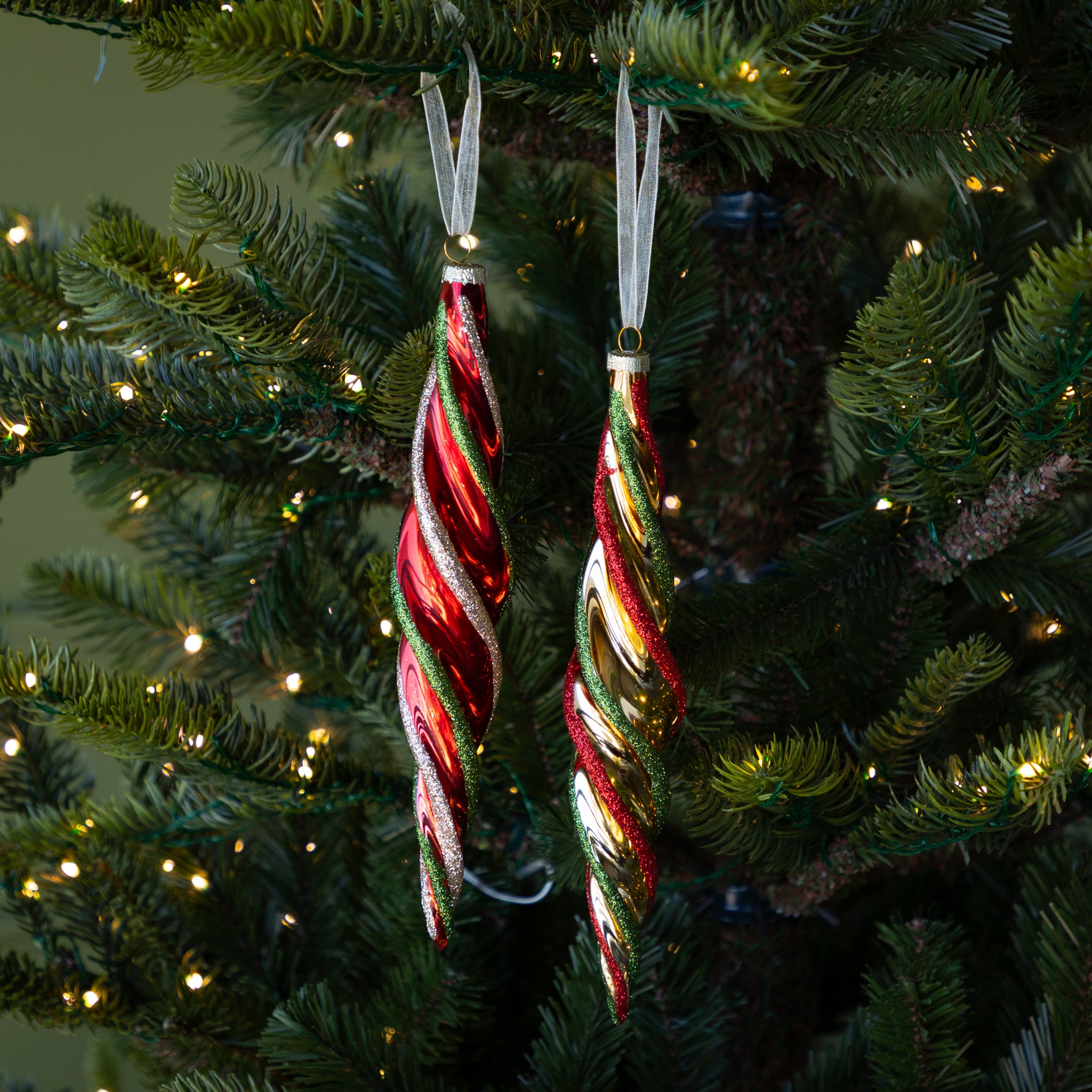Red &amp; Gold Twirl Ornaments hanging on a lit tree.