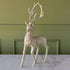 Decorative deer figurine with glittery texture on a marble surface against a green wall.