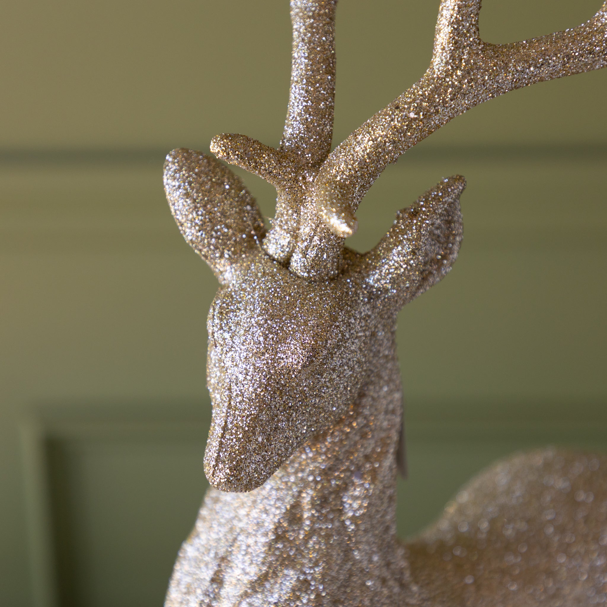 Decorative deer figure with glittery antlers against a green background.