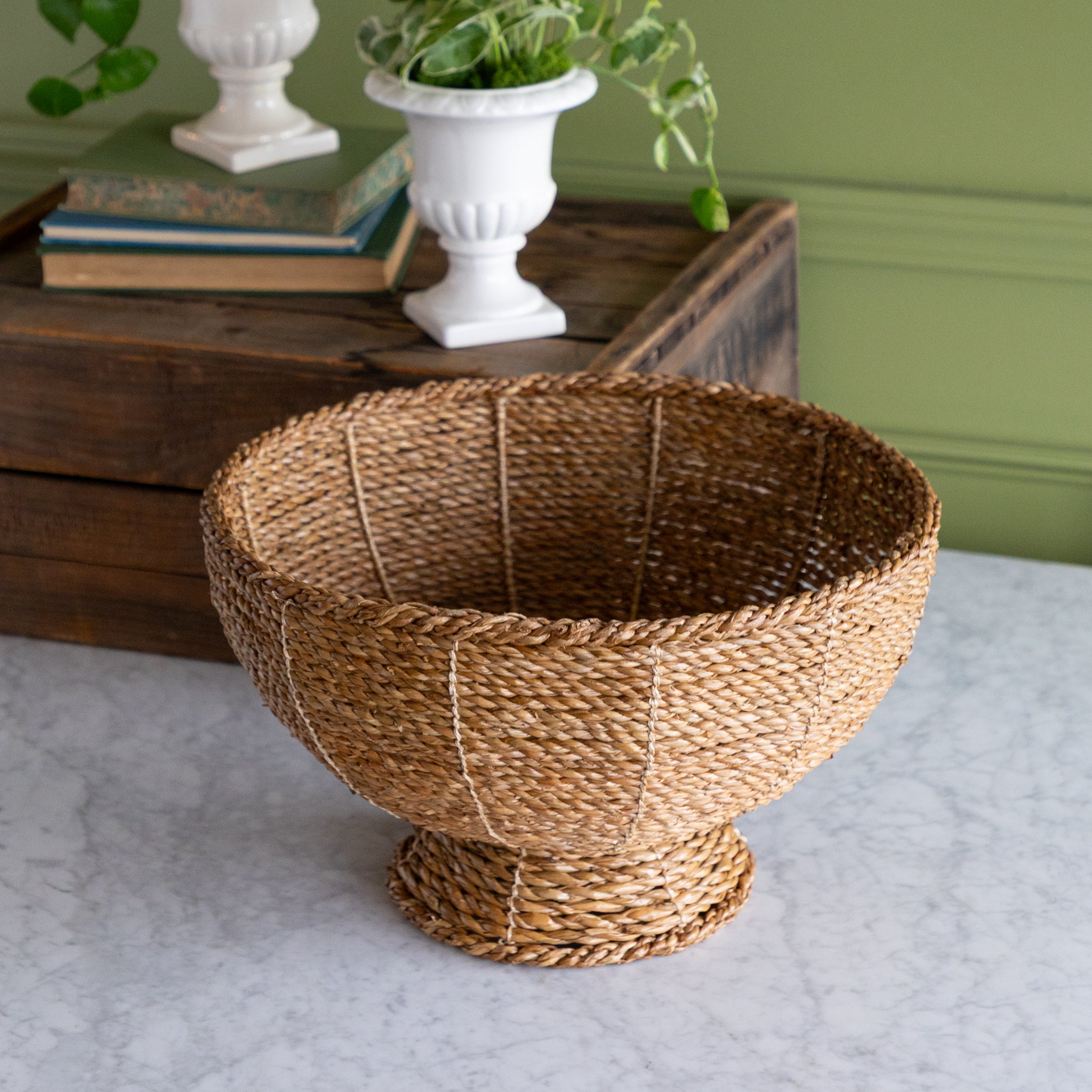 Natural Rope Weave Bowl on marble surface with a wooden box, books and a plant in the background.