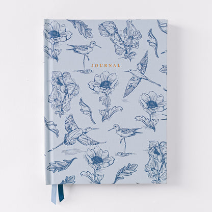 Blue notebook with various birds and flower illustrations on it with Journal printed in the middle at the top