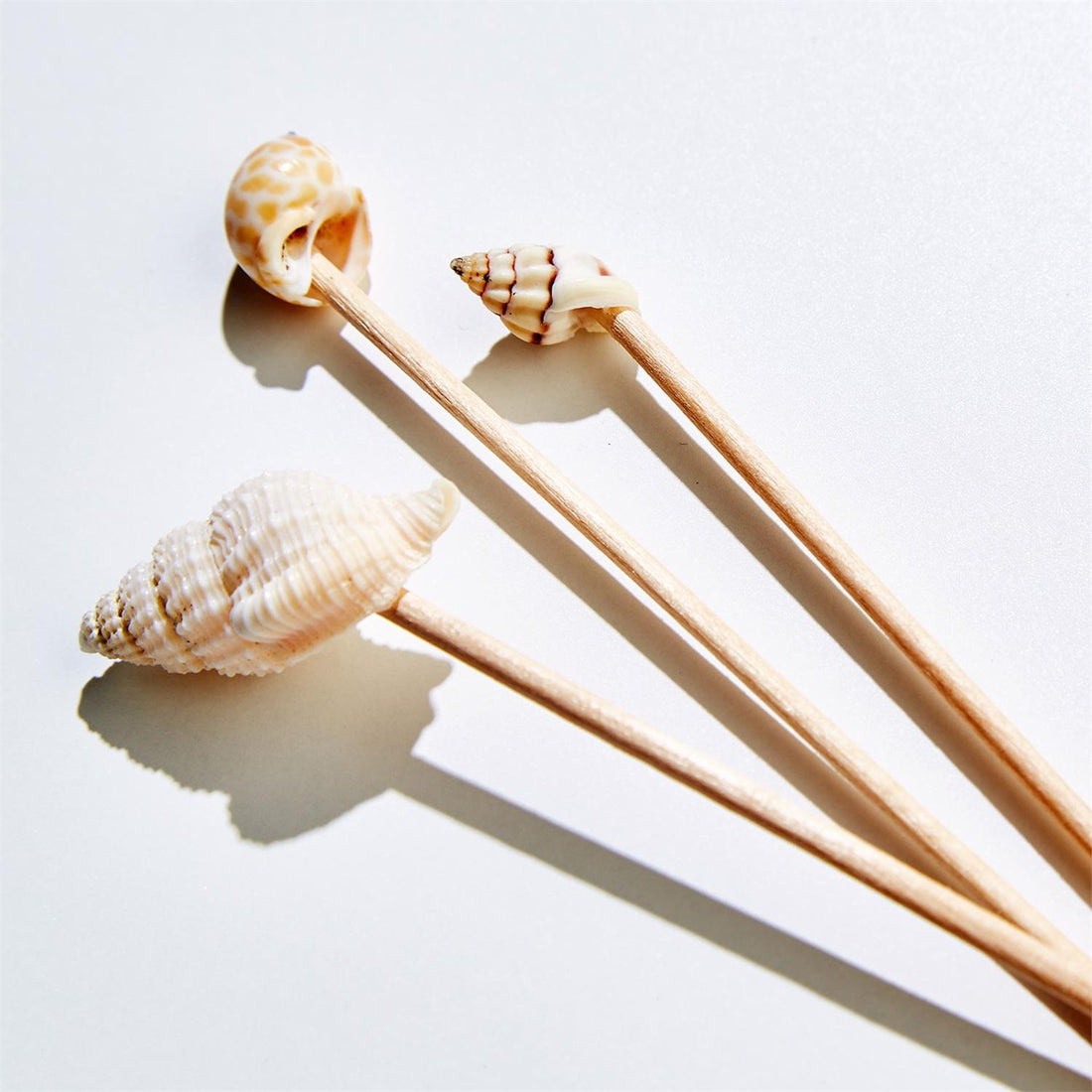 Wooden picks with shell decorations on a light background.