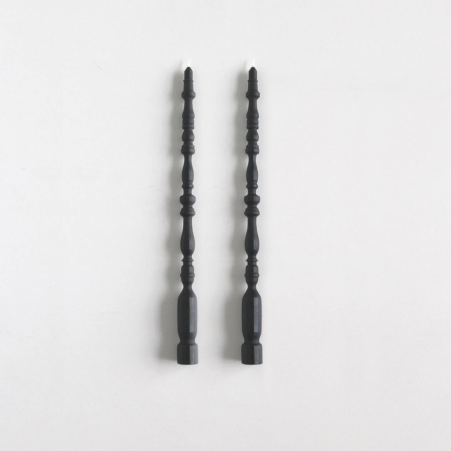 2 taper candles shaped like table spindle legs in charcoal. 