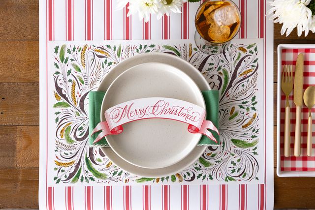 Decorative Christmas placemat with a plate and cutlery on a wooden table.