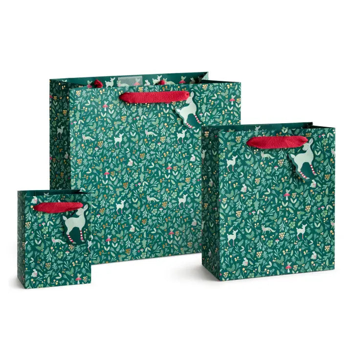 Three green gift bags with a white deer and floral pattern, featuring red handles, displayed on a clean white background.
