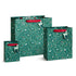Three green gift bags with a white deer and floral pattern, featuring red handles, displayed on a clean white background.