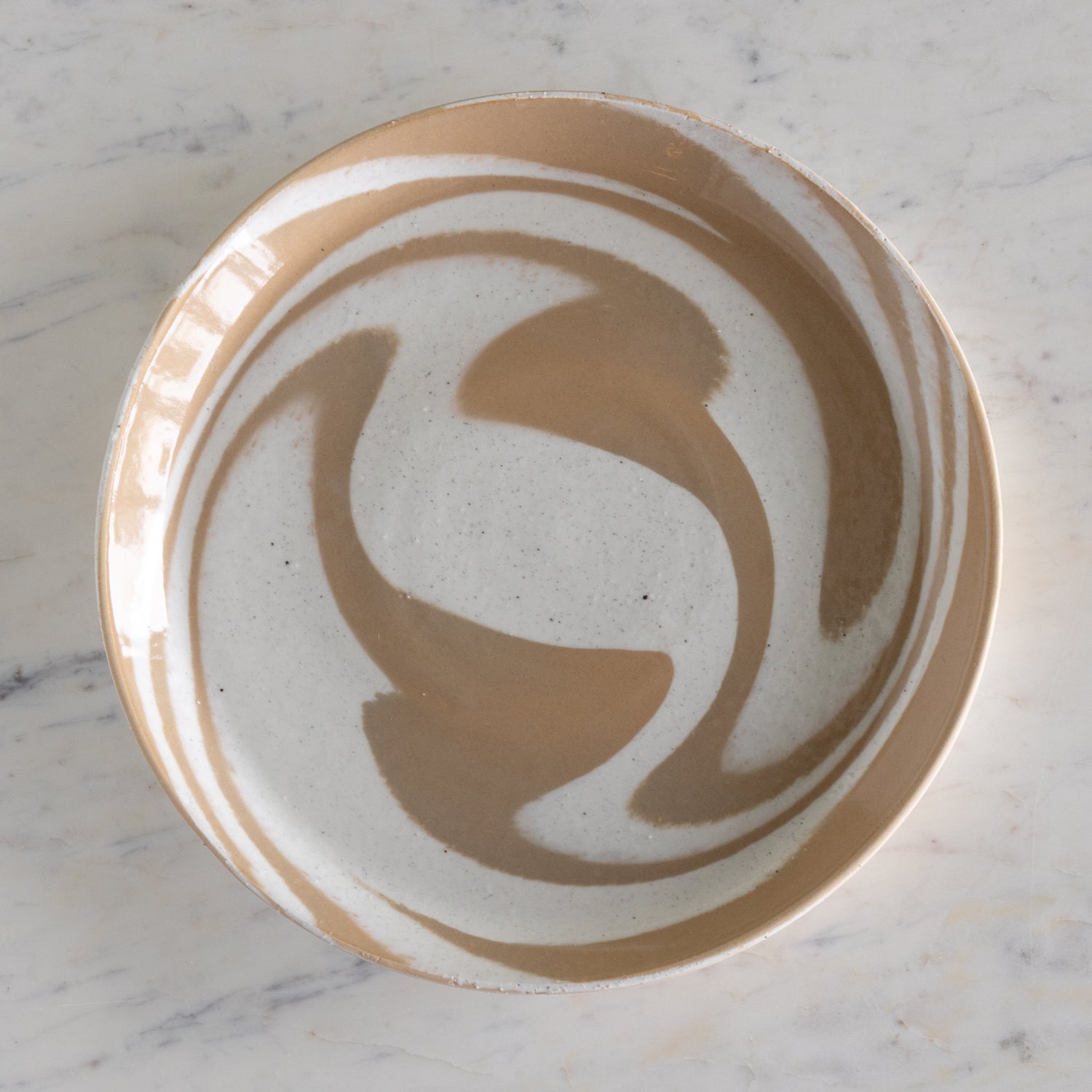 Ceramic plate with artistic brown design on a marble surface.