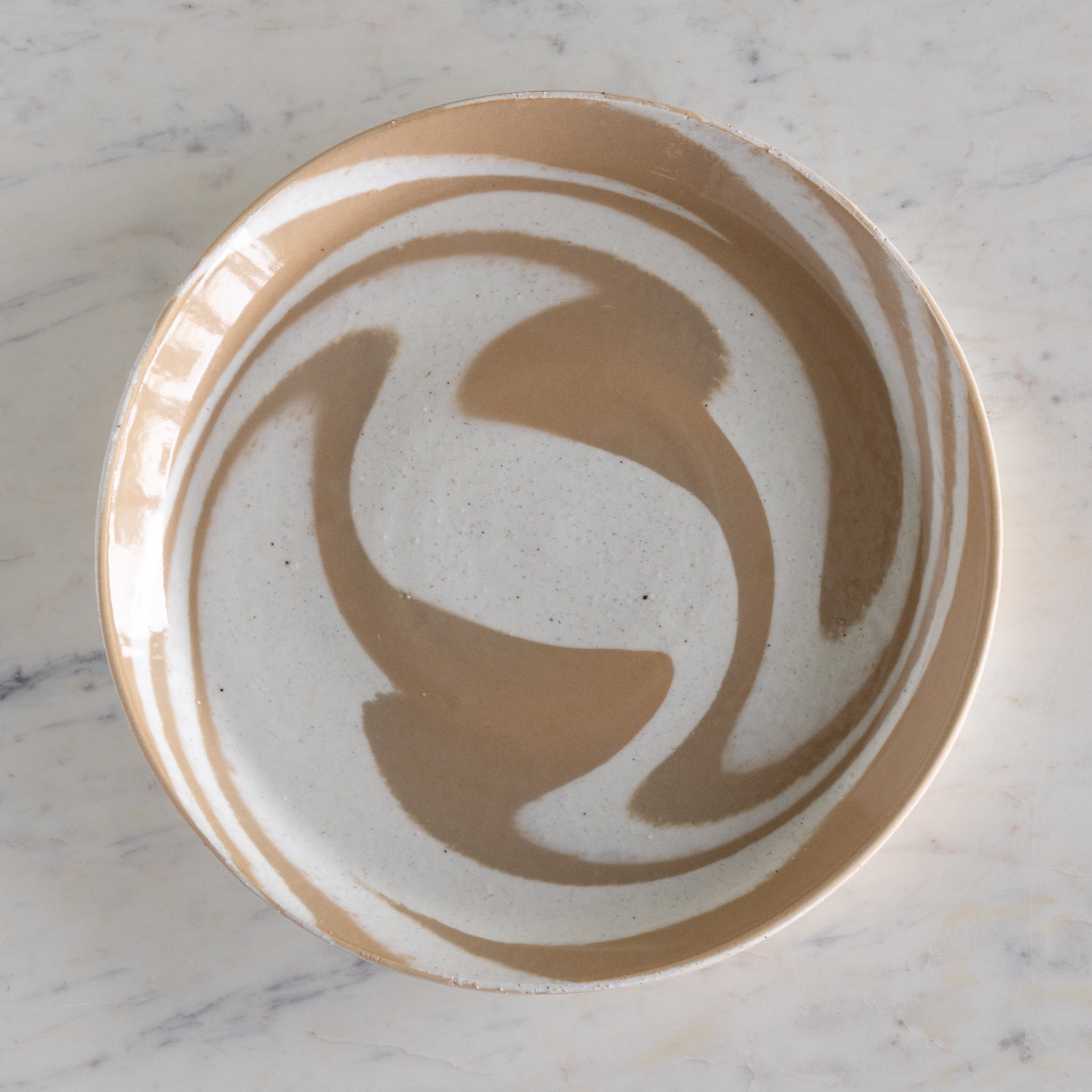 Ceramic plate with artistic brown design on a marble surface.