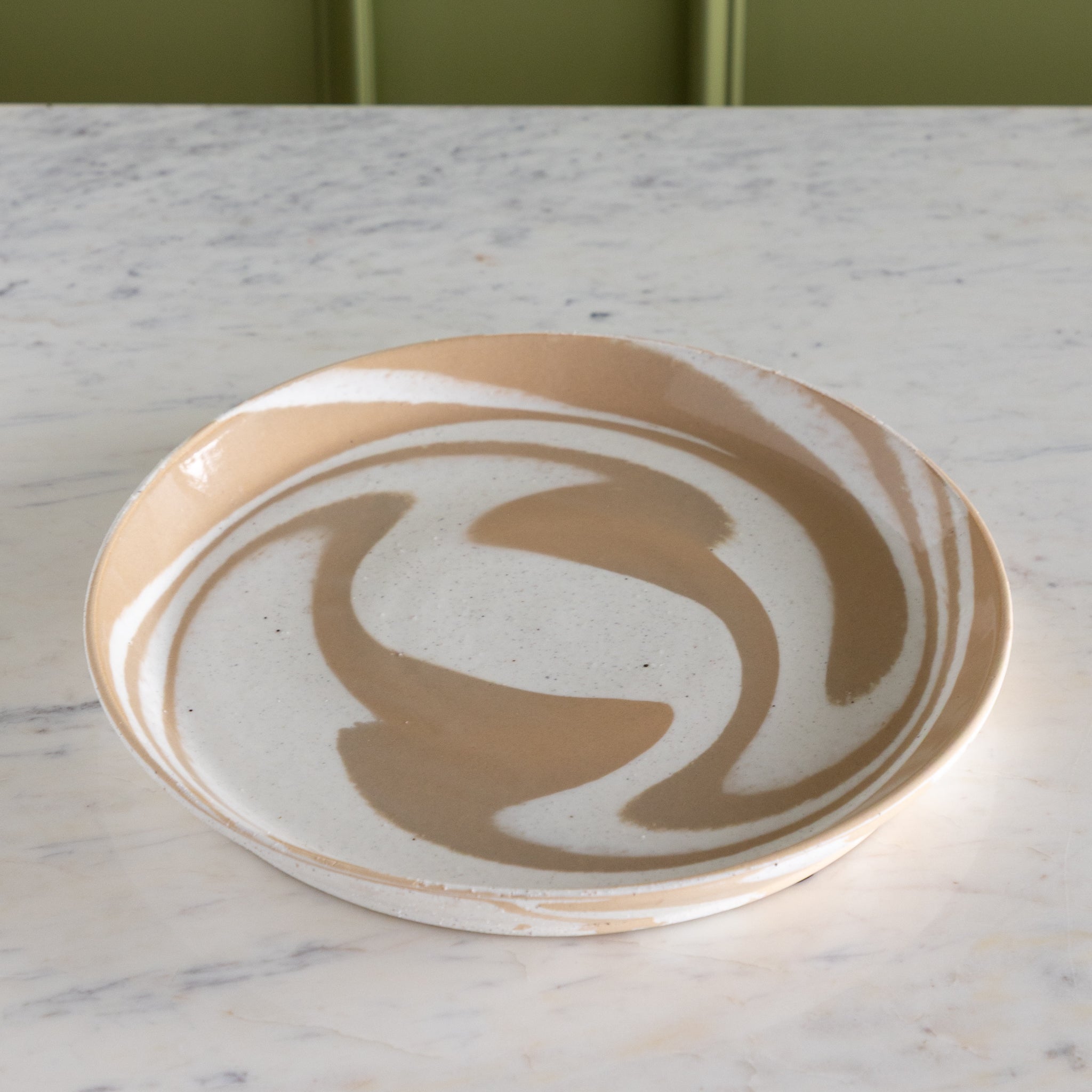 Ceramic plate with a swirling design on a marble surface.