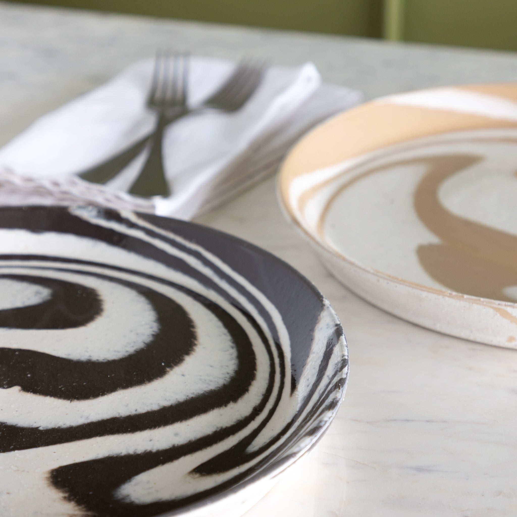 Two ceramic plates with unique patterns on a marble surface.