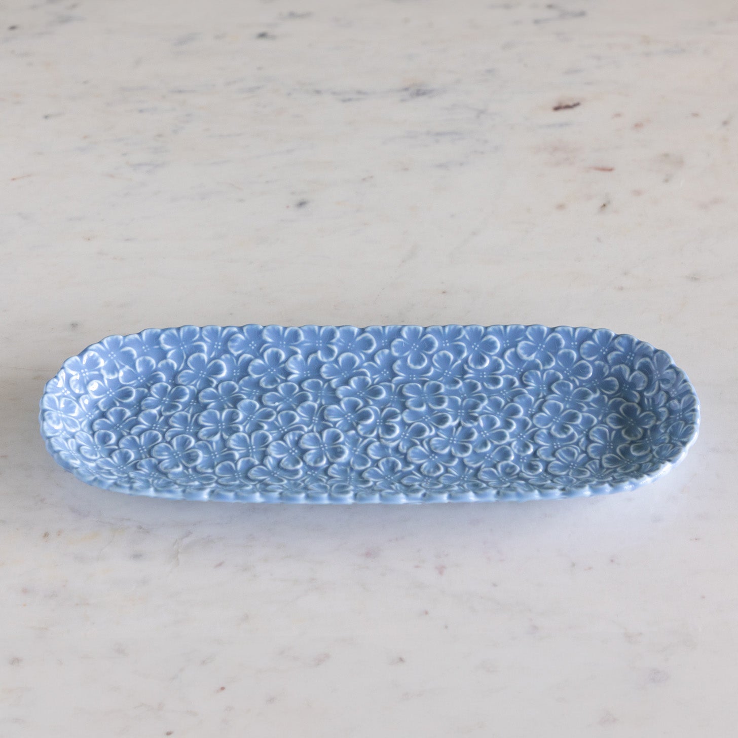 Blue textured oval dish on a light marble background.