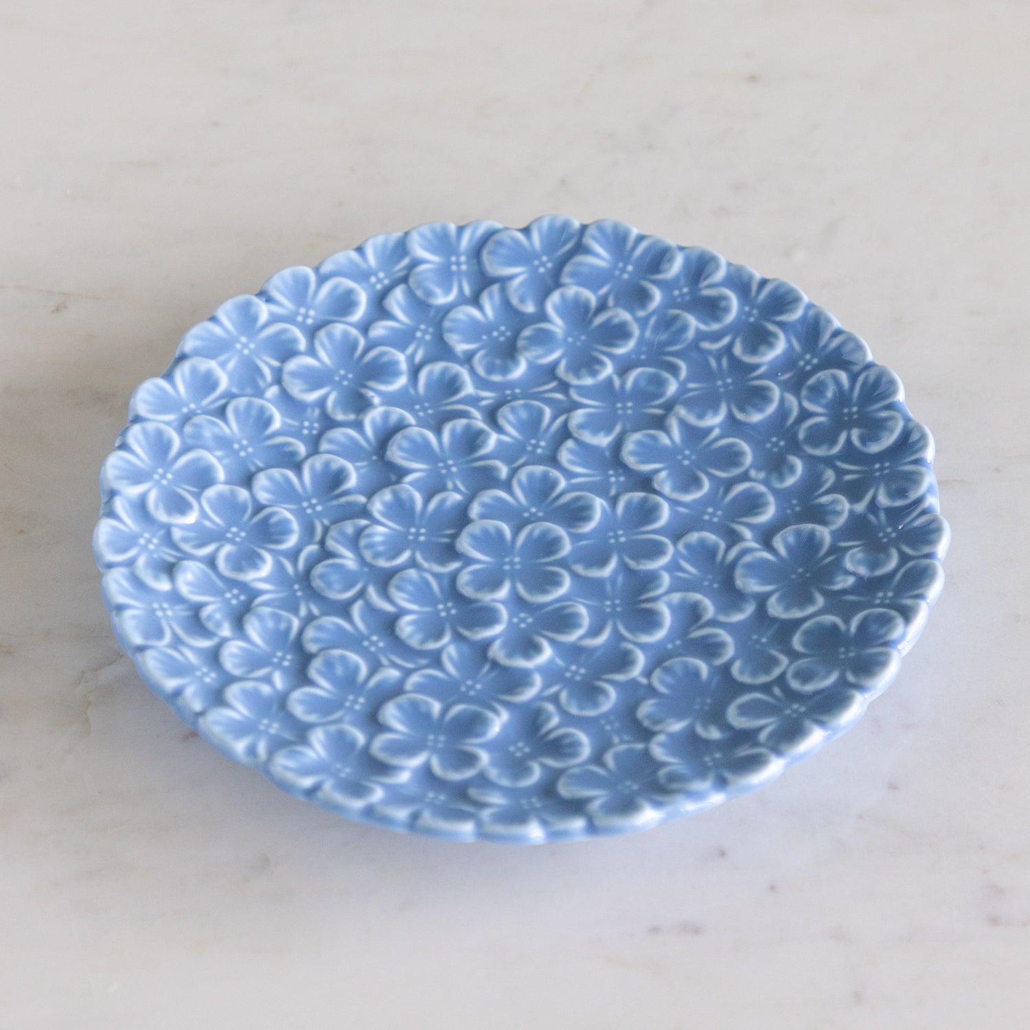 Blue ceramic plate with floral pattern on a white marble surface.