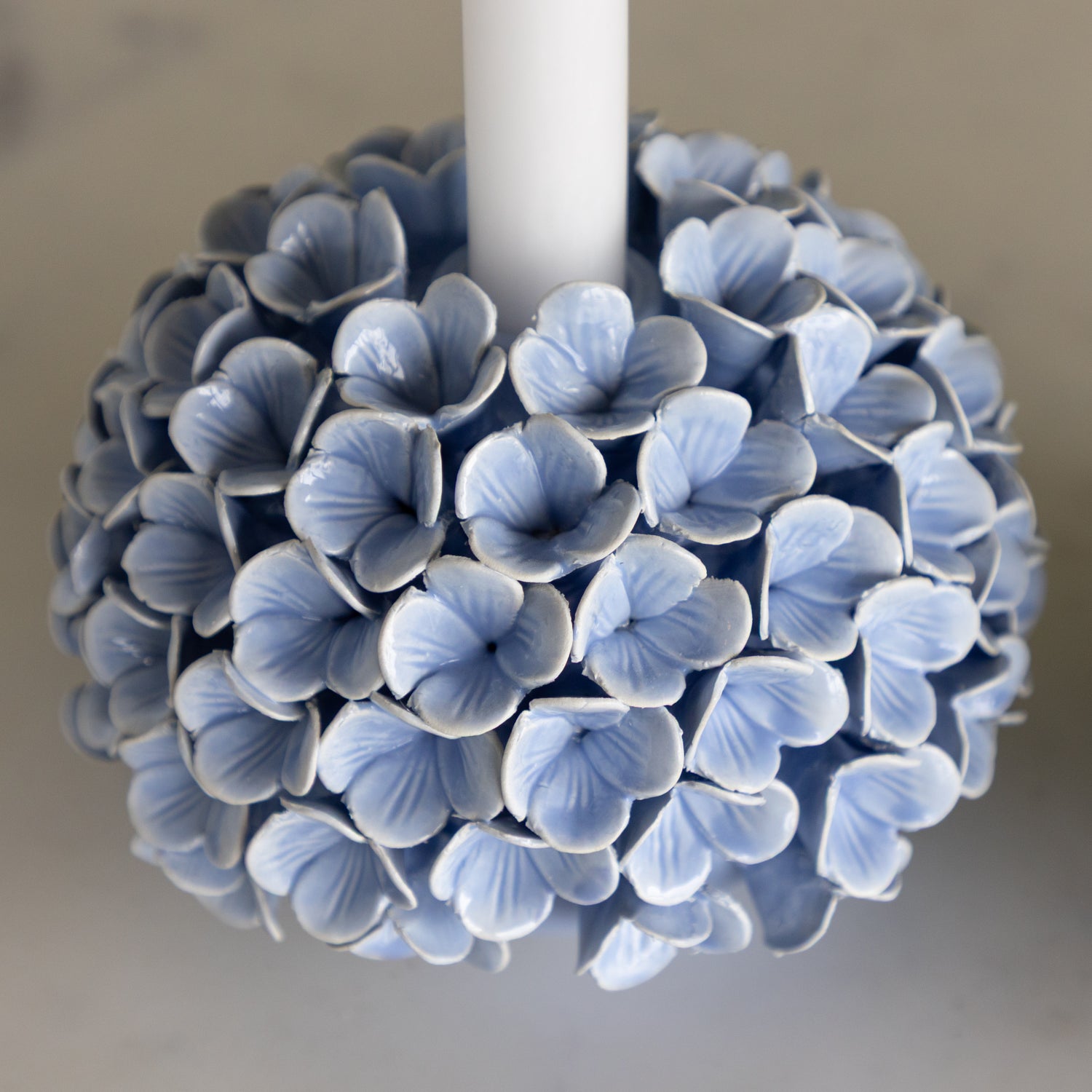 Decorative candle holder with blue flower-like design on a neutral background.