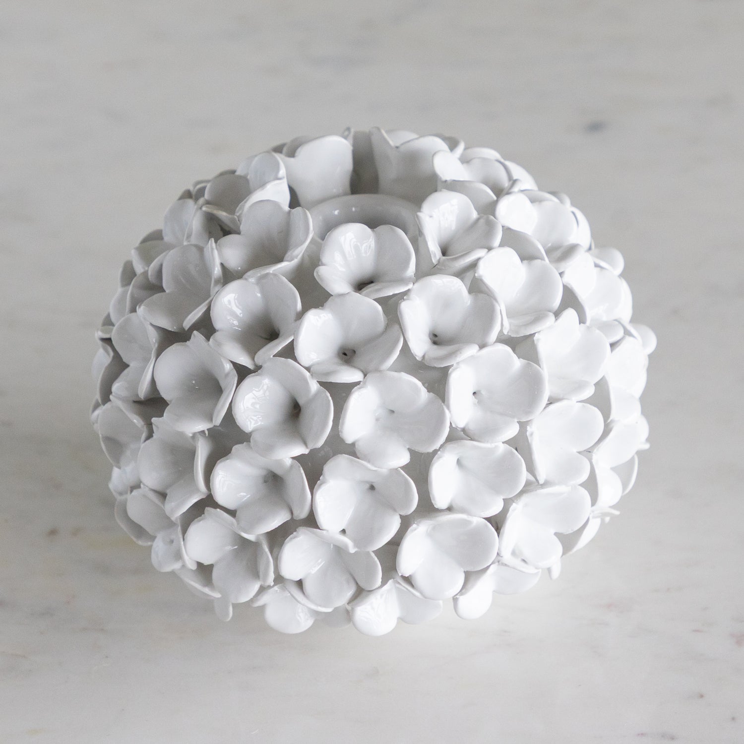 White spherical decorative object with petal-like structures on a light gray background