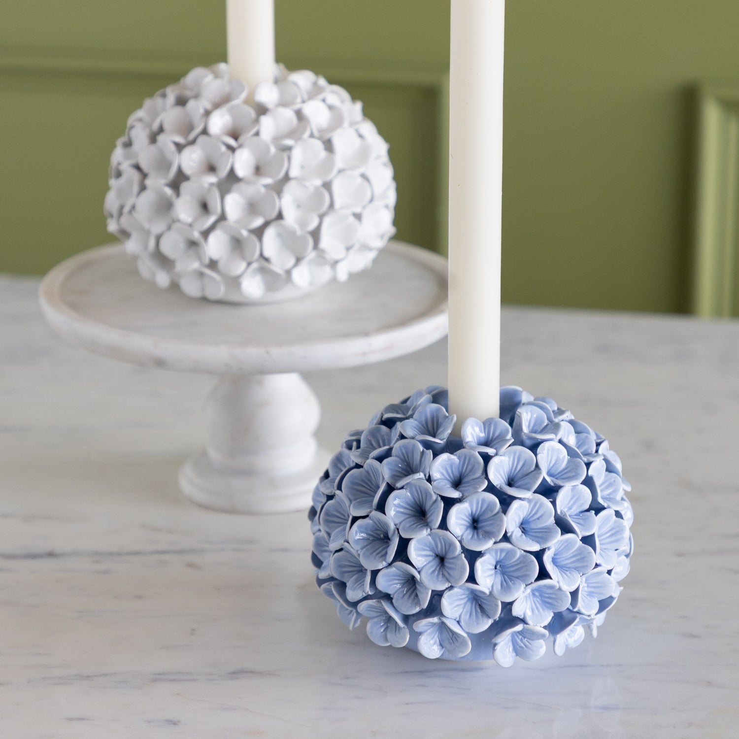 Decorative candle holders shaped like white and blue floral balls on a marble surface.
