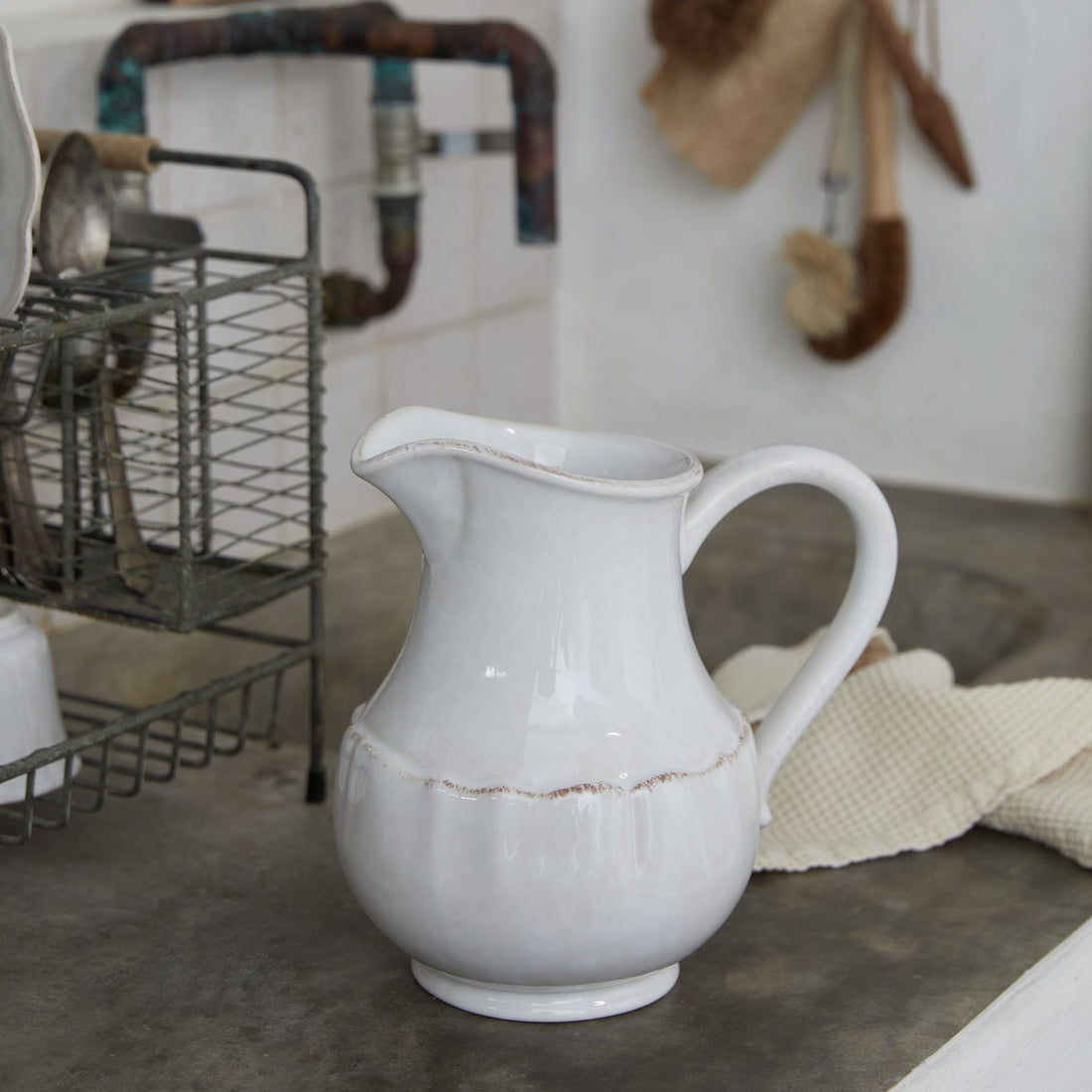White ceramic pitcher on a kitchen counter with a blurred background
