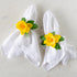 Daffodil Spray Napkin Ring Holders around two white linen napkins.