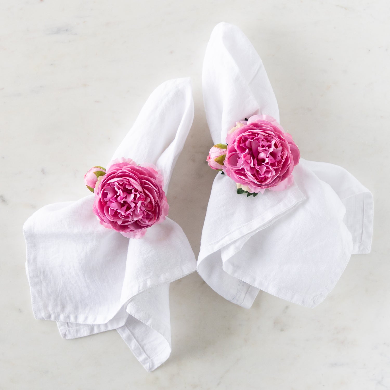 Pink Buttercup &amp; Bud Napkin Rings around two white linen napkins.