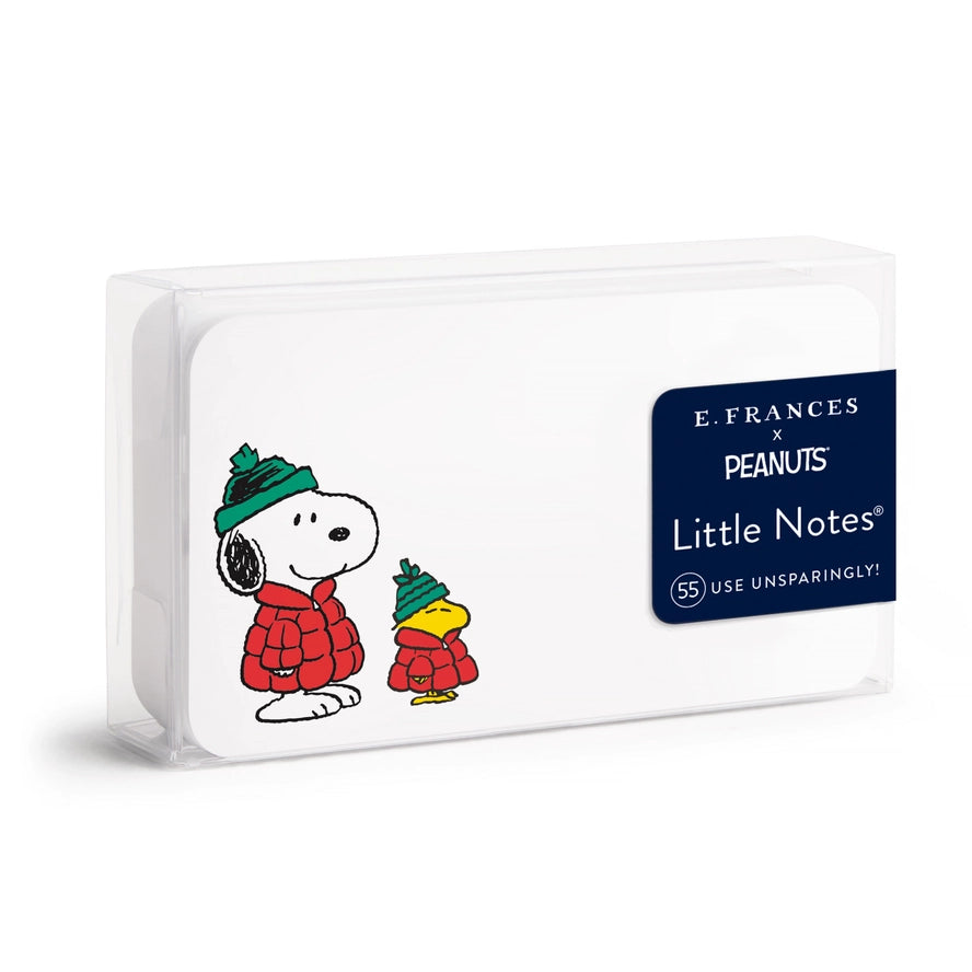E. Frances x Peanuts Little Notes notebook in a clear plastic sleeve, featuring Snoopy and Woodstock in red winter coats and hats on a white cover with a navy blue brand label.