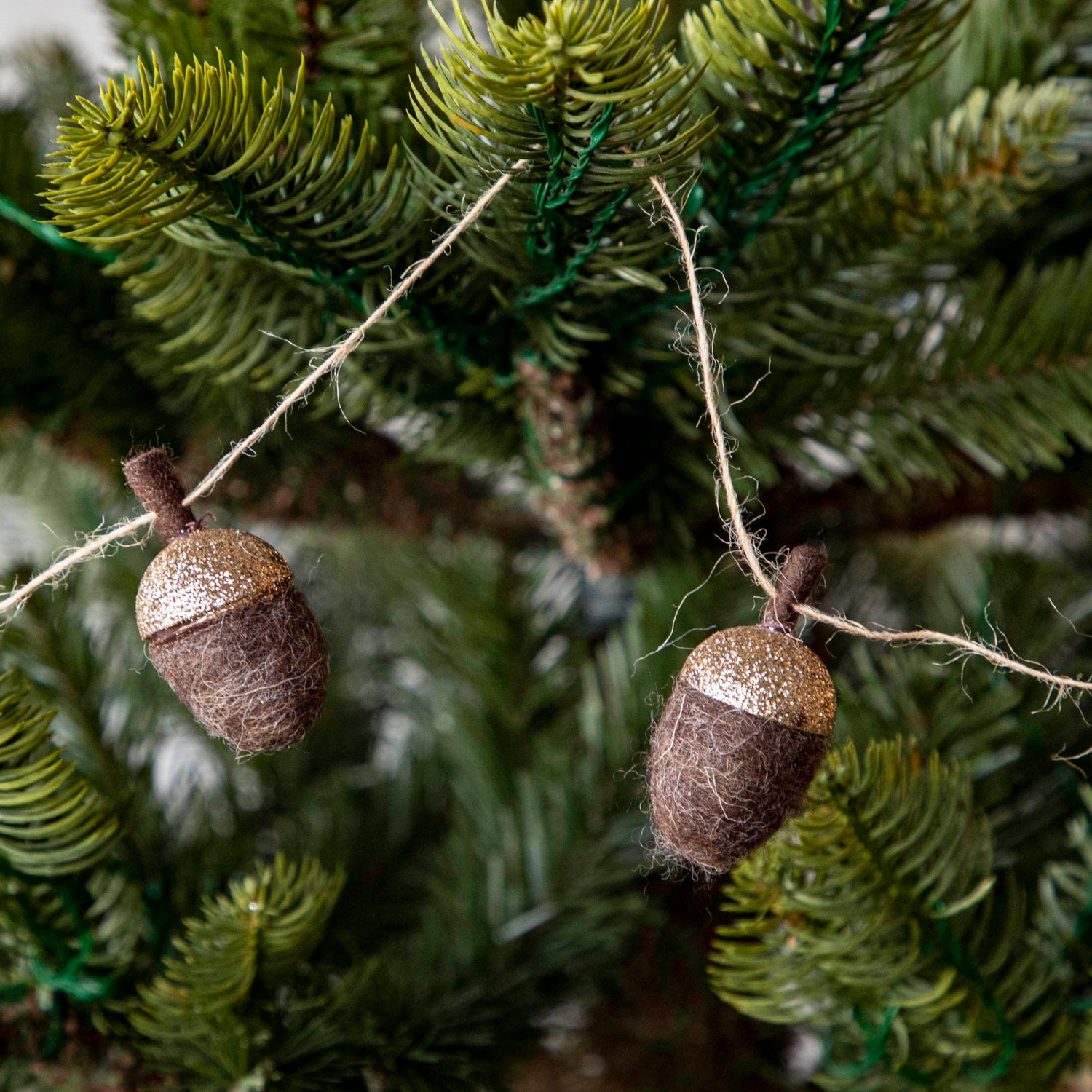 Close up of woolen acorn garland in a tree showing its glittered top .