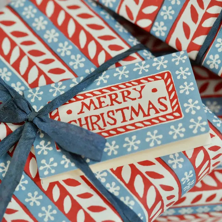 A wrapped Christmas present with a Merry Christmas card tucked into the ribbon.