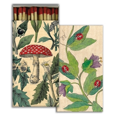 Matchbox with botanical design featuring mushrooms and leaves on a beige background.