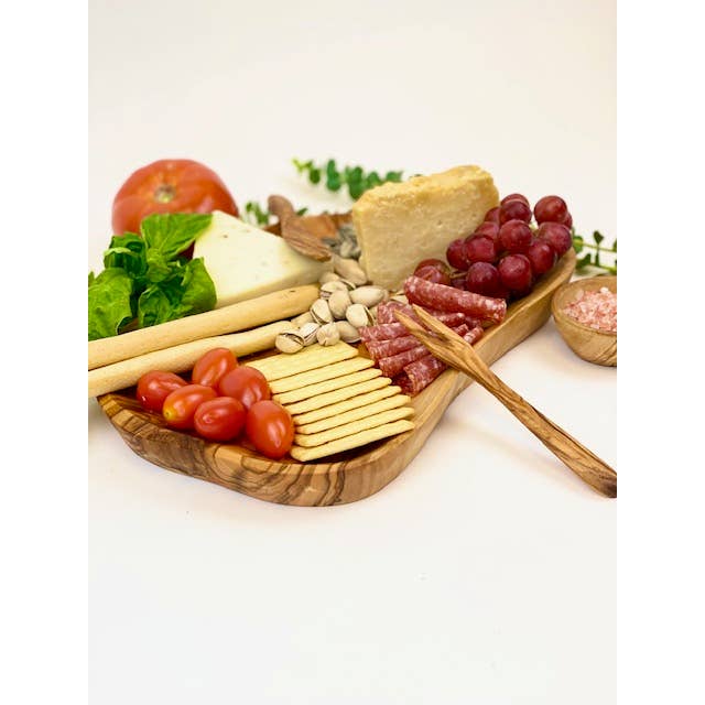 A serving board made of olive wood with charcuterie displayed on it. 