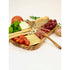 A serving board made of olive wood with charcuterie displayed on it. 