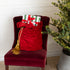 Red Velvet Santa Bag with two gold tassels and gifts inside, on a red chair next to a decorated Christmas tree.