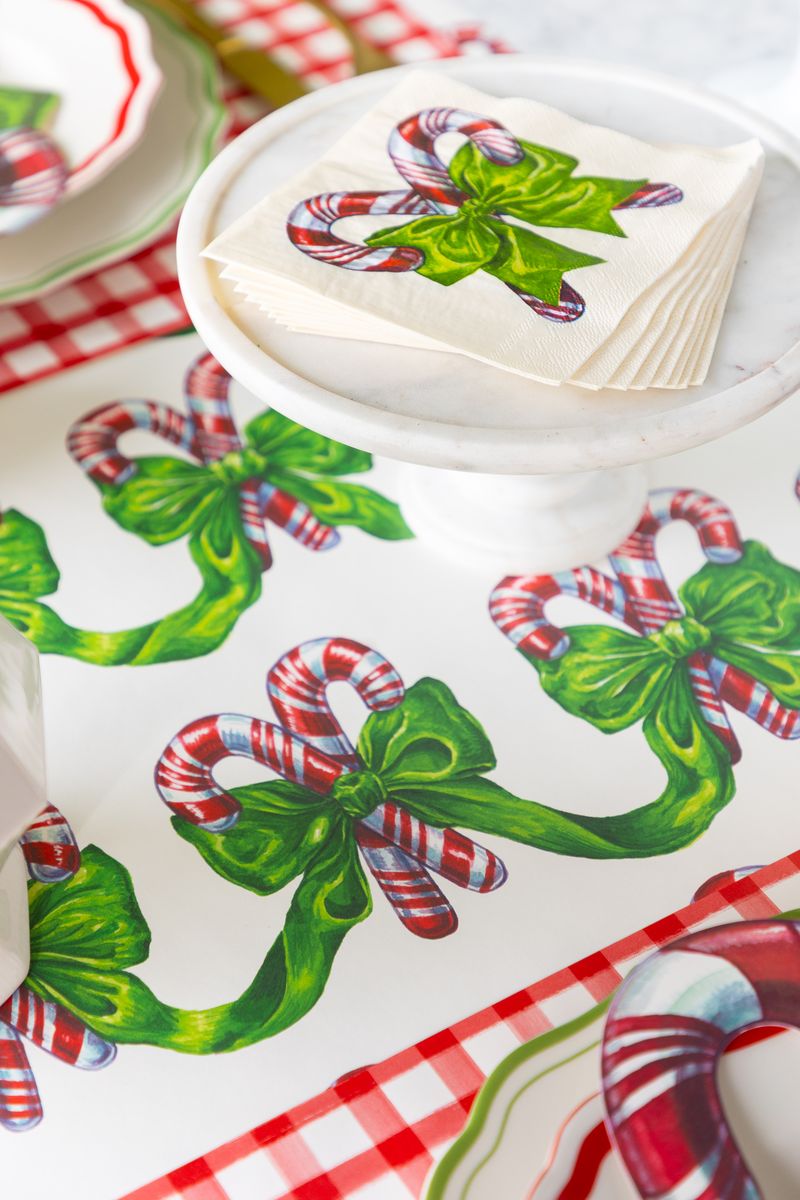 A candy cane themed runner on a table with matching cocktail napkins. 
