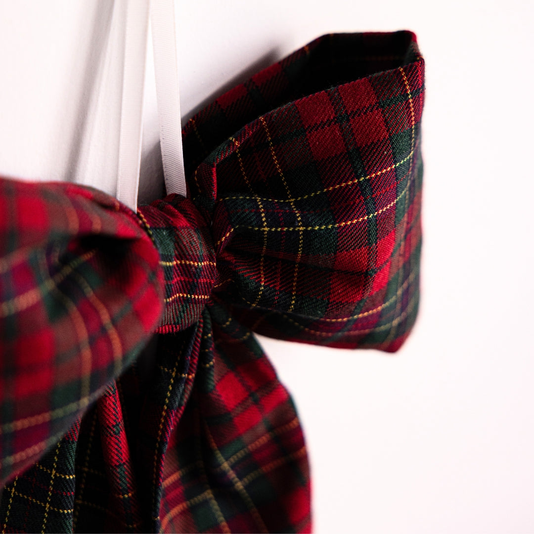 Close-up of a red and green plaid bow on a white background