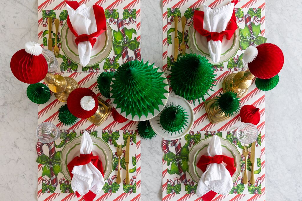 Two Christmas-themed place settings with red and green decorations on a white surface.