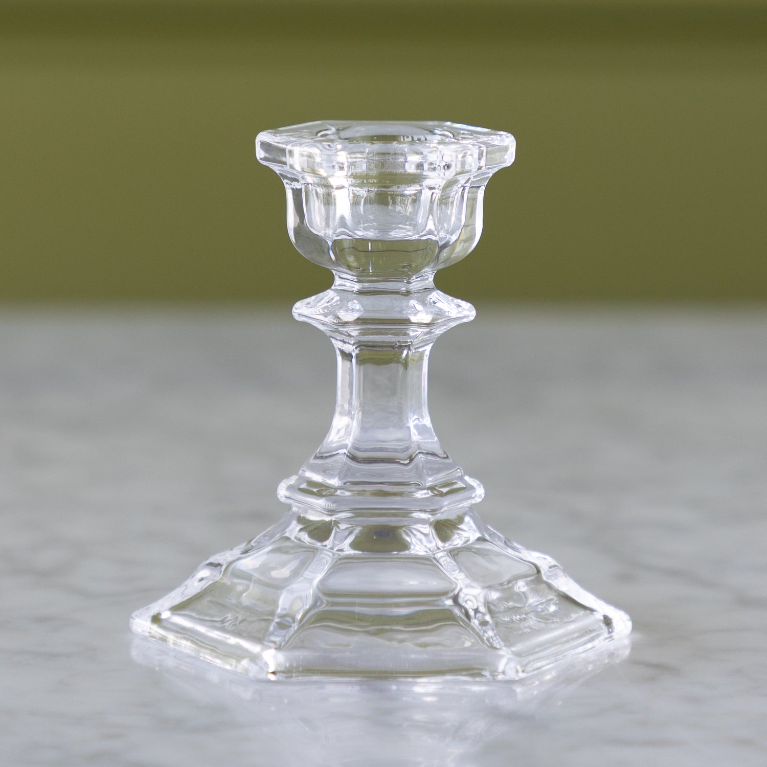 Clear glass candlestick on a neutral background.