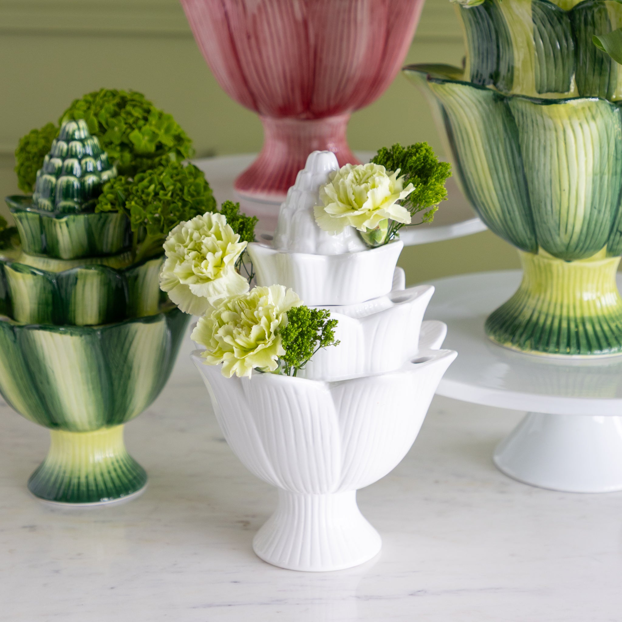 Decorative table setting with green and white floral arrangements in various vases.