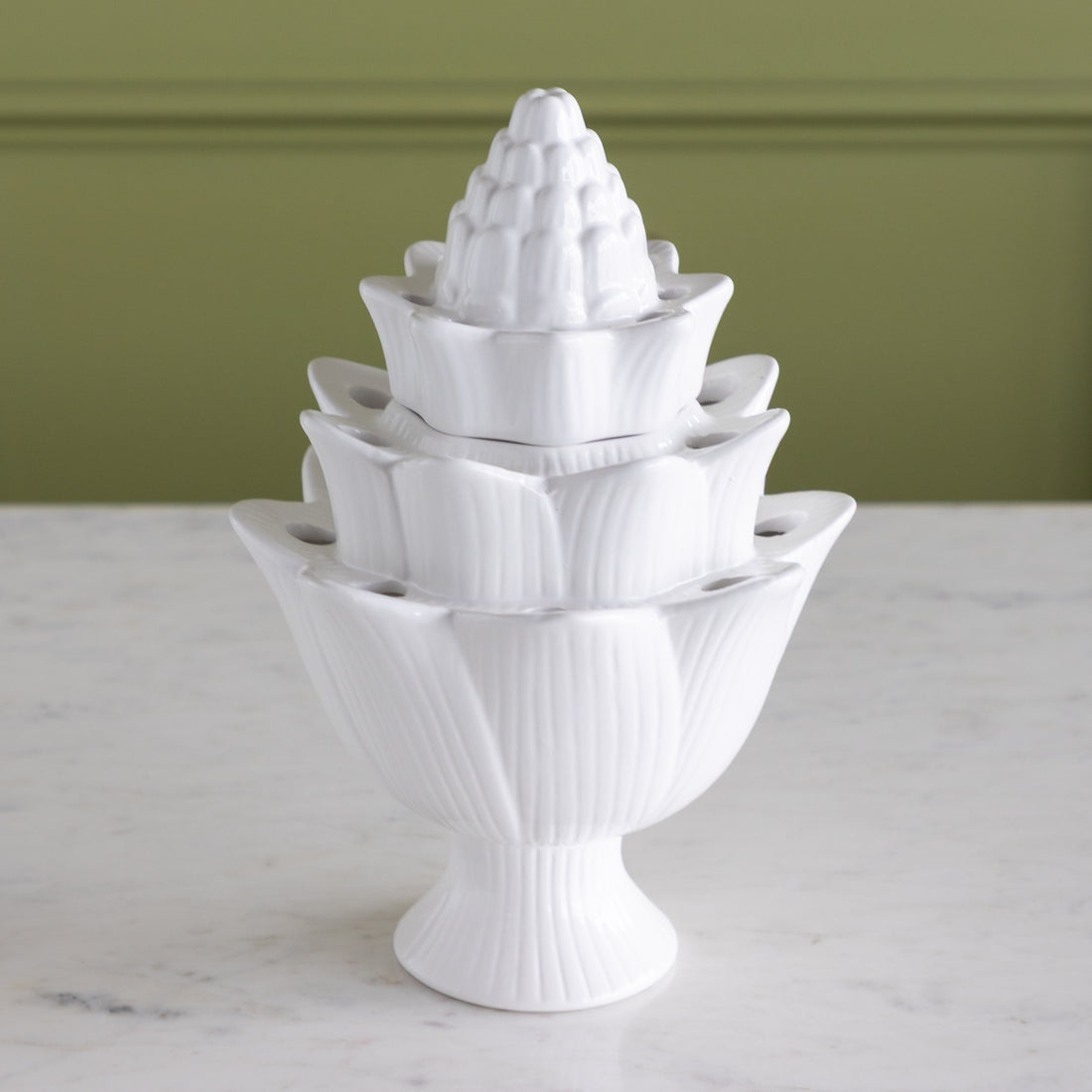 White ceramic flower tulipiere with layered design on a marble surface.