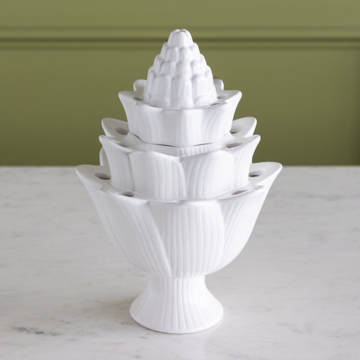 White ceramic flower tulipiere with layered design on a marble surface.