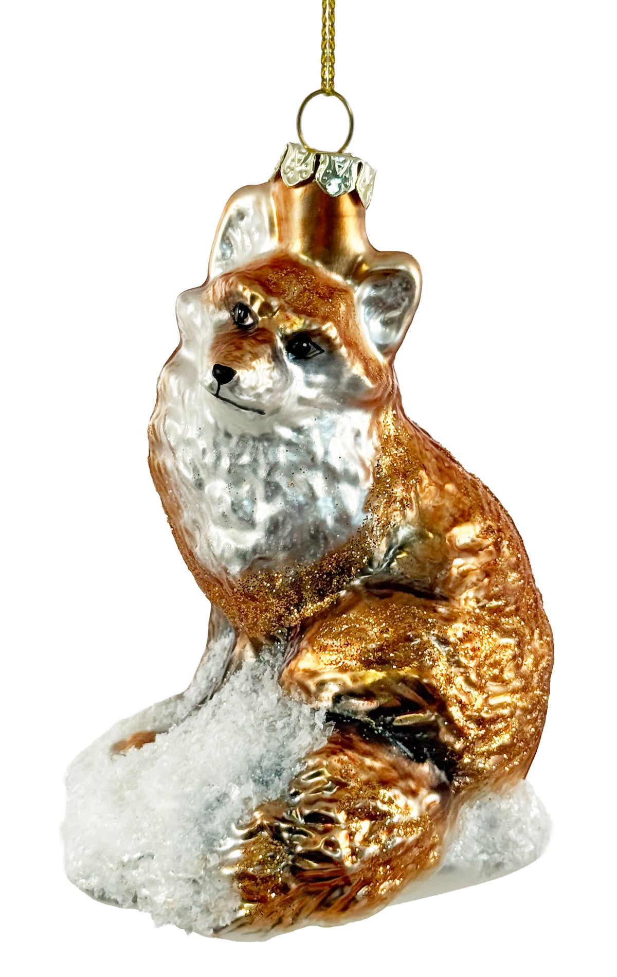 A decorative glass ornament shaped like a fox sitting on a snowy base, with a gold hanging loop at the top. The fox has a metallic copper-brown coat with white and silver areas, photographed on a plain white background.