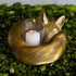 Gold fox-shaped candle holder with a lit candle on a green leafy background