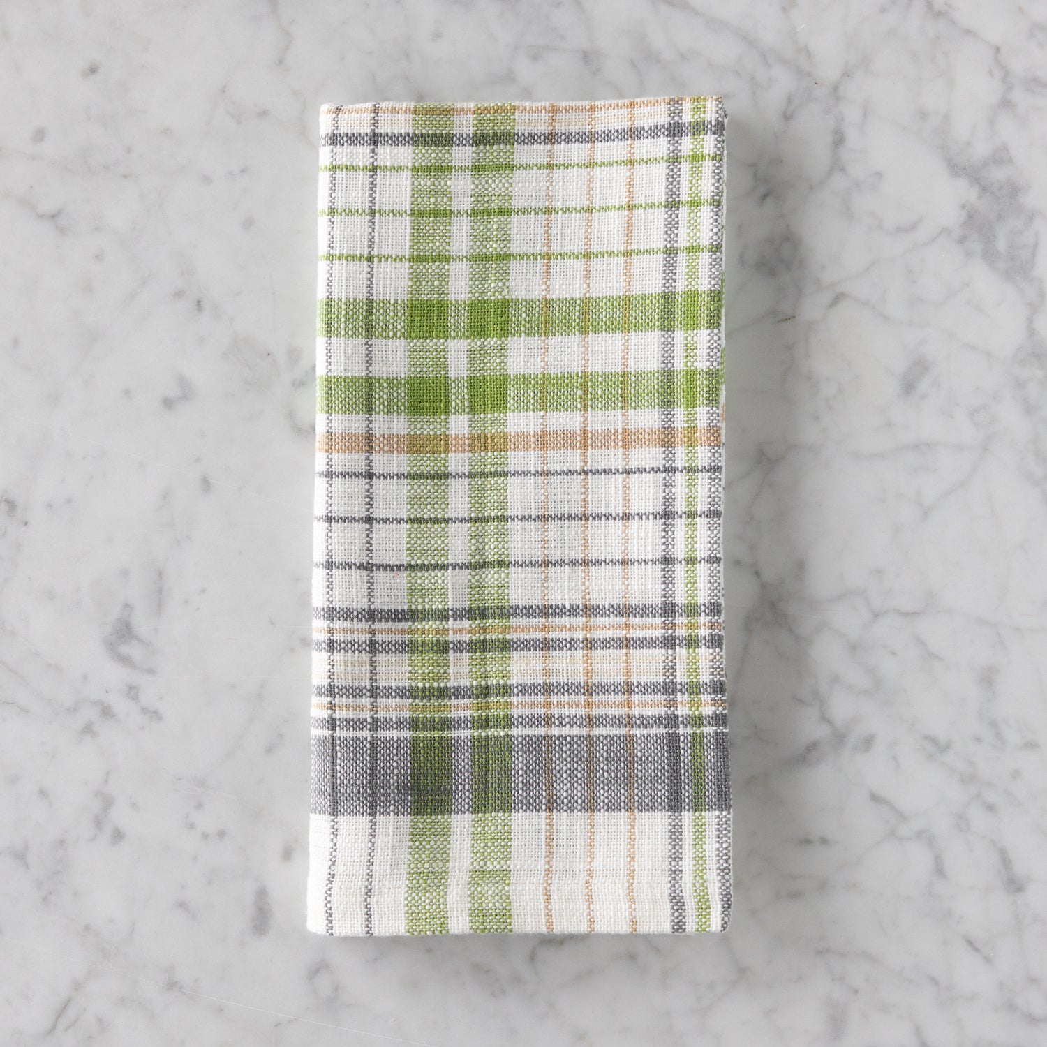 Plaid towel with green, white, and brown pattern on a marble surface.