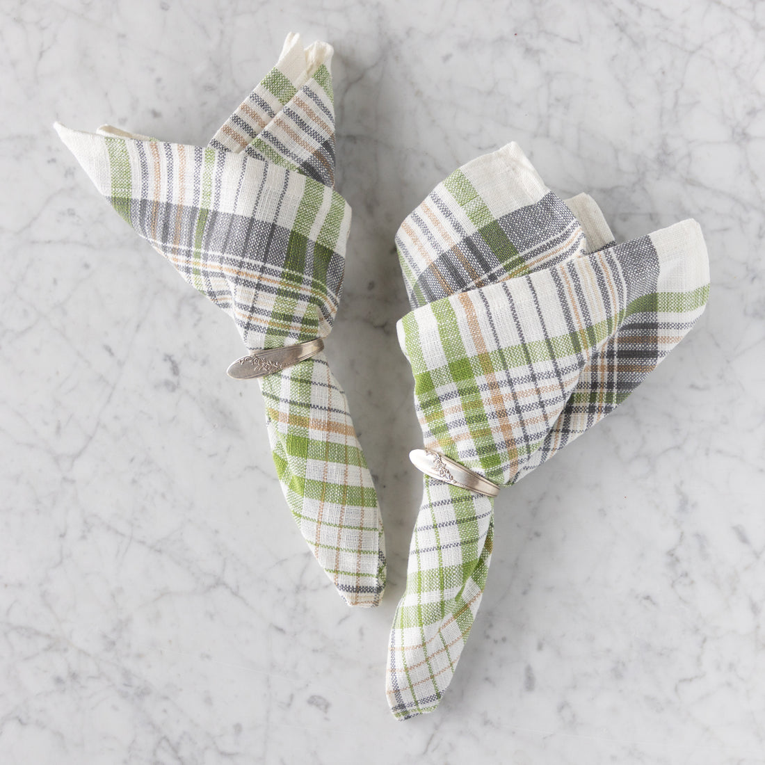 Plaid napkins folded into triangles on a marble surface.