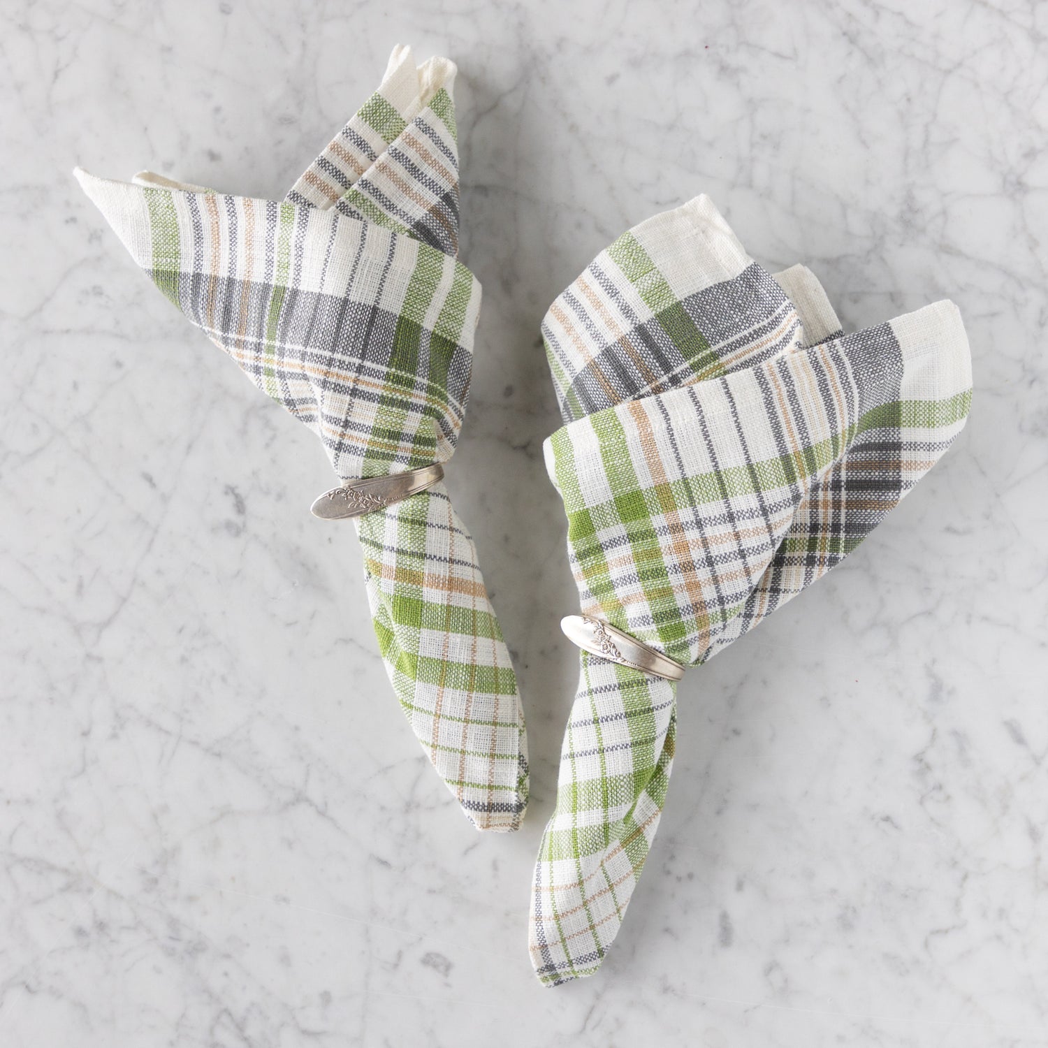 Plaid napkins folded into triangles on a marble surface.