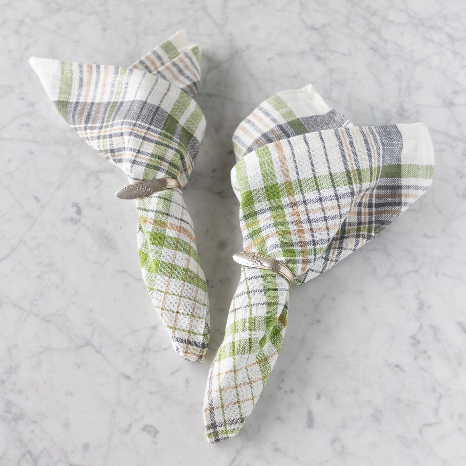 Two folded checkered napkins on a marble surface.