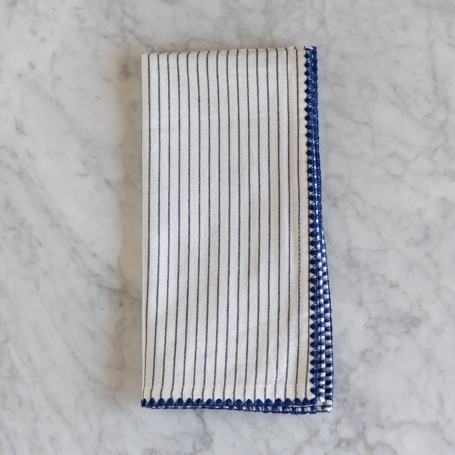 Folded striped napkin with blue and white pattern on a marble surface.