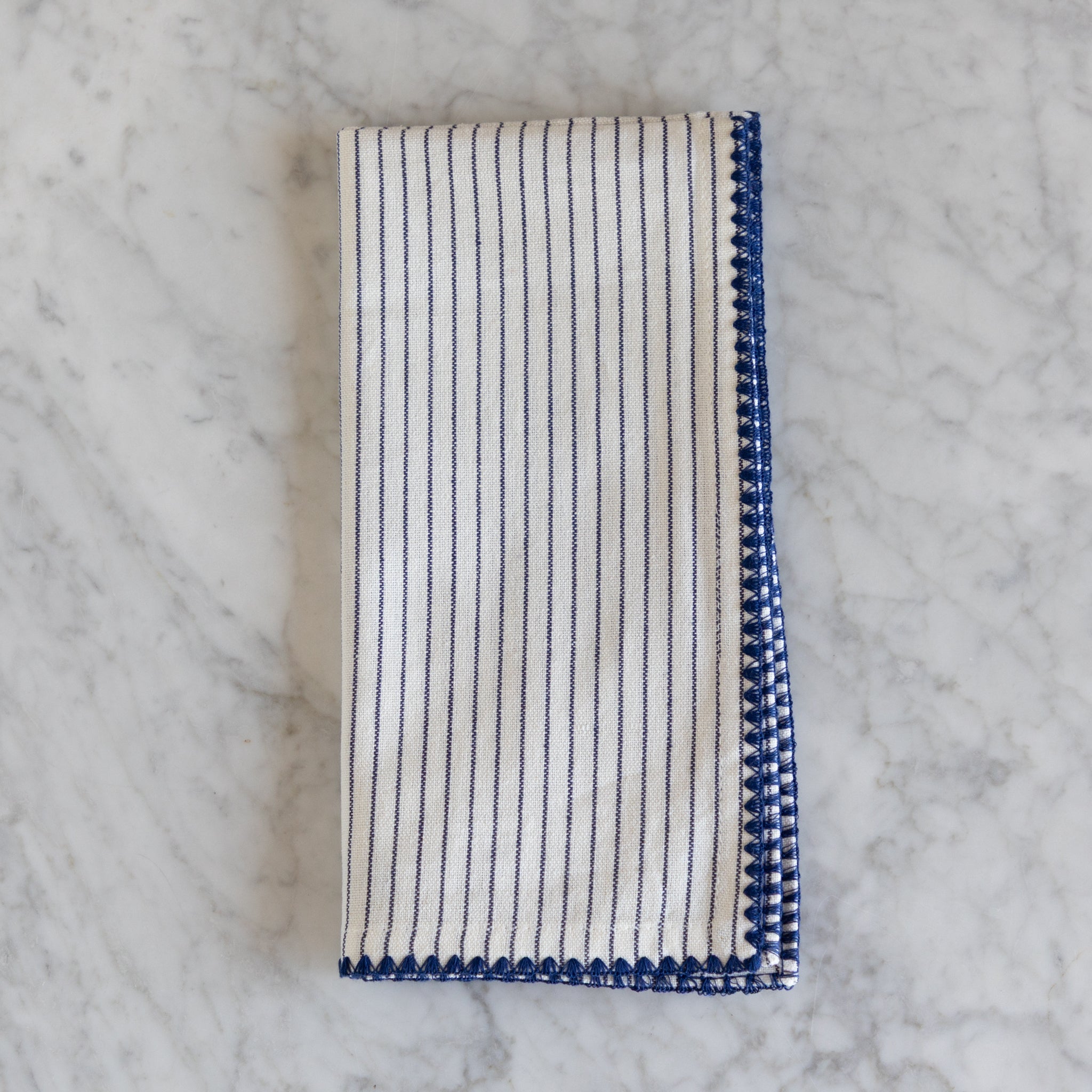 Folded striped napkin with blue and white pattern on a marble surface.