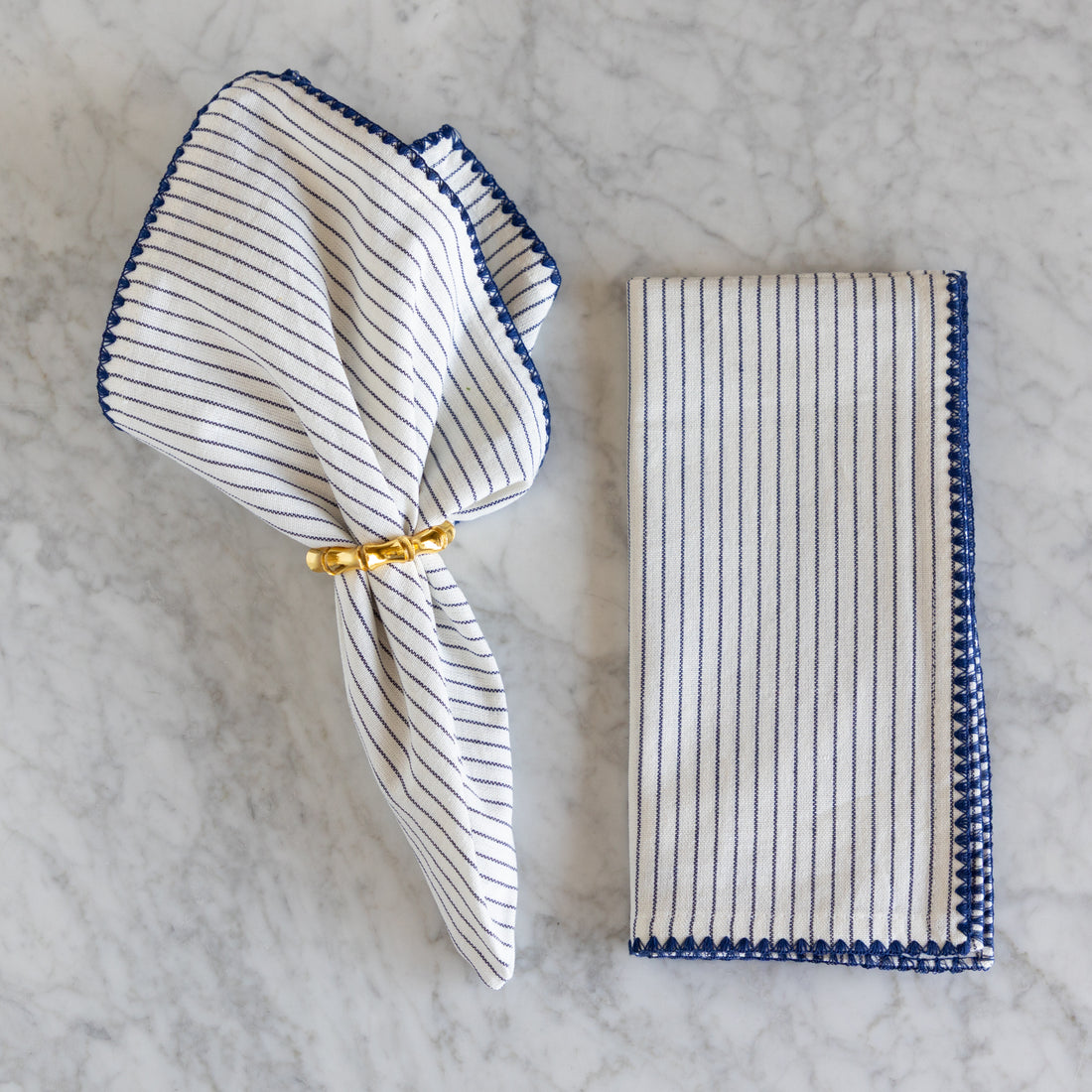 Striped napkin with a gold ring on a marble surface.