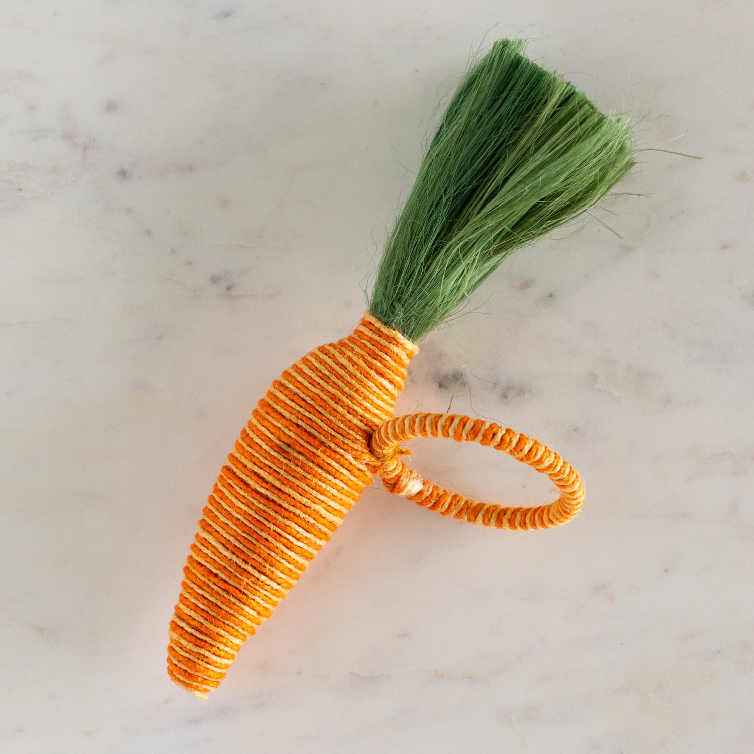 Carrot-shaped napkin ring on a marble background.